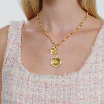 Gold lariat necklace with delicate flower pendants, shown on model.
