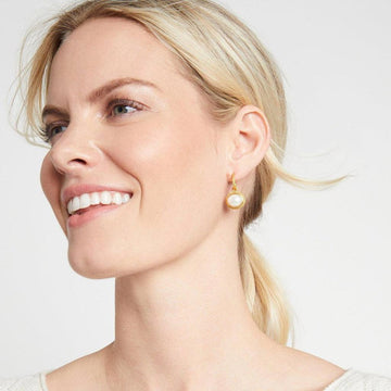 Gold hoop earrings with a white pearl charm; elegant jewelry detail.
