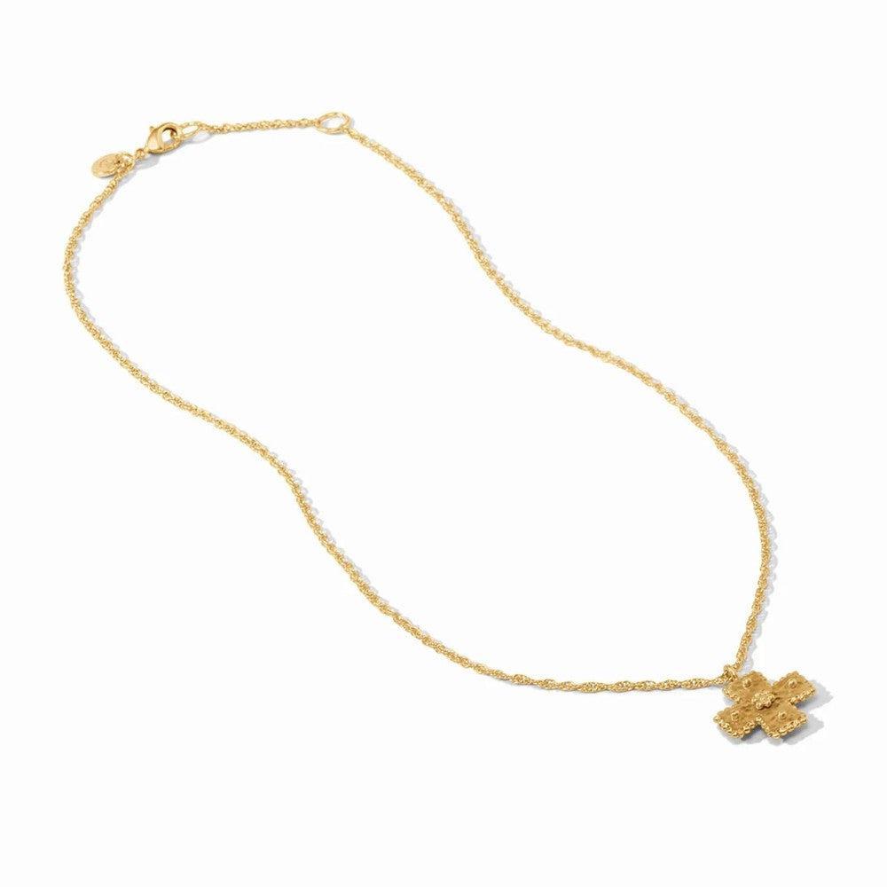 Gold cross pendant necklace on delicate chain; ornate texture.
