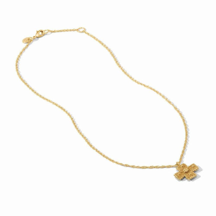 Gold cross pendant necklace on delicate chain; ornate texture.
