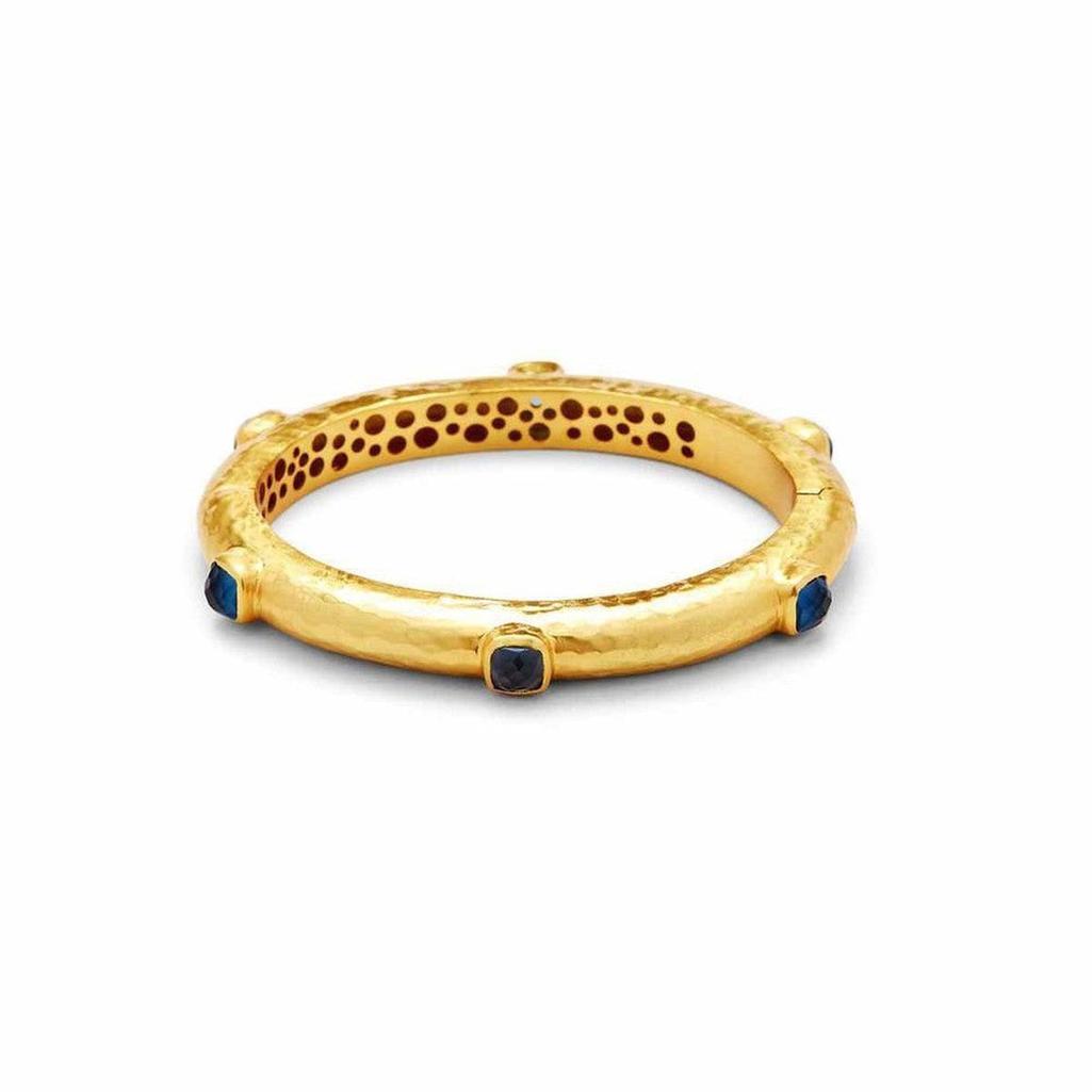 Gold hinged bangle with dark blue gemstones.
