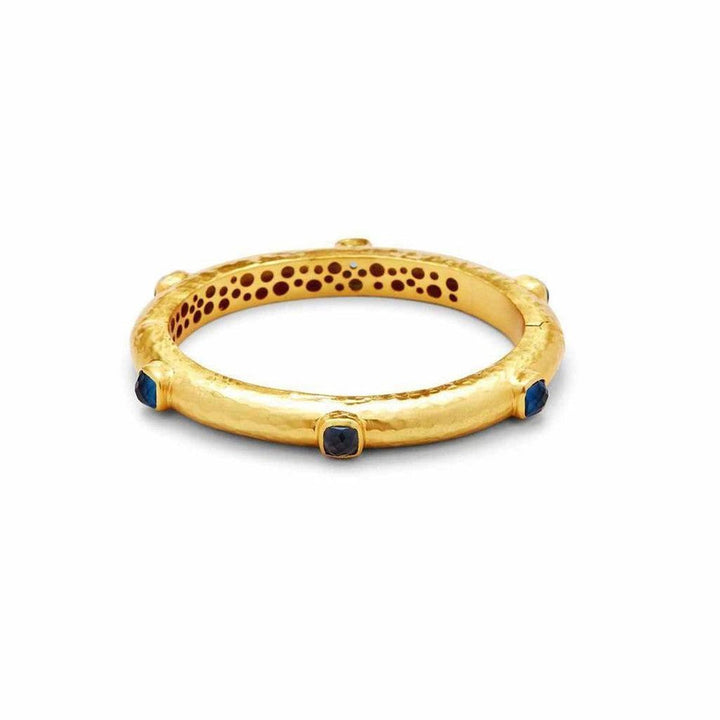 Gold hinged bangle with dark blue gemstones.
