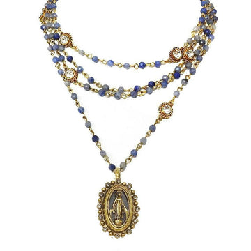 Layered blue stone and gold beaded necklace featuring a Virgin Mary pendant.
