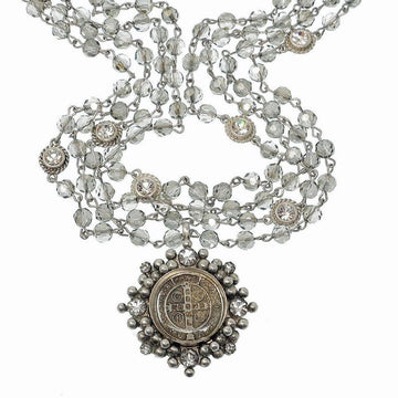 Multi-strand crystal bead necklace with ornate silver pendant.
