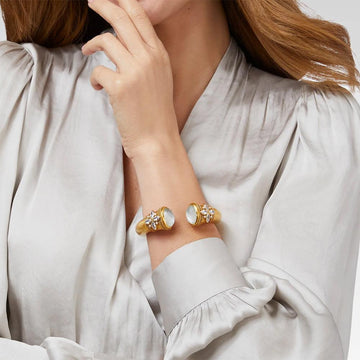 Gold cuff bracelet with opal accents, worn on a model's wrist.
