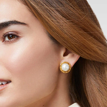 Close-up of gold beaded pearl earrings on a woman's ear.
