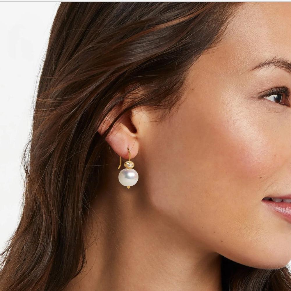 Gold pearl drop earrings with a small gemstone accent.
